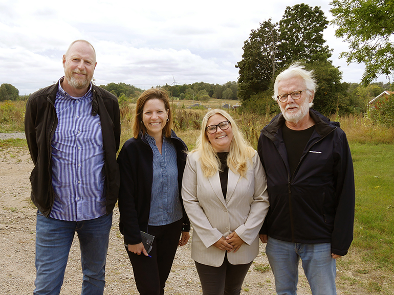 Fyra personer står på en gräsplätt med träd runtomkring.