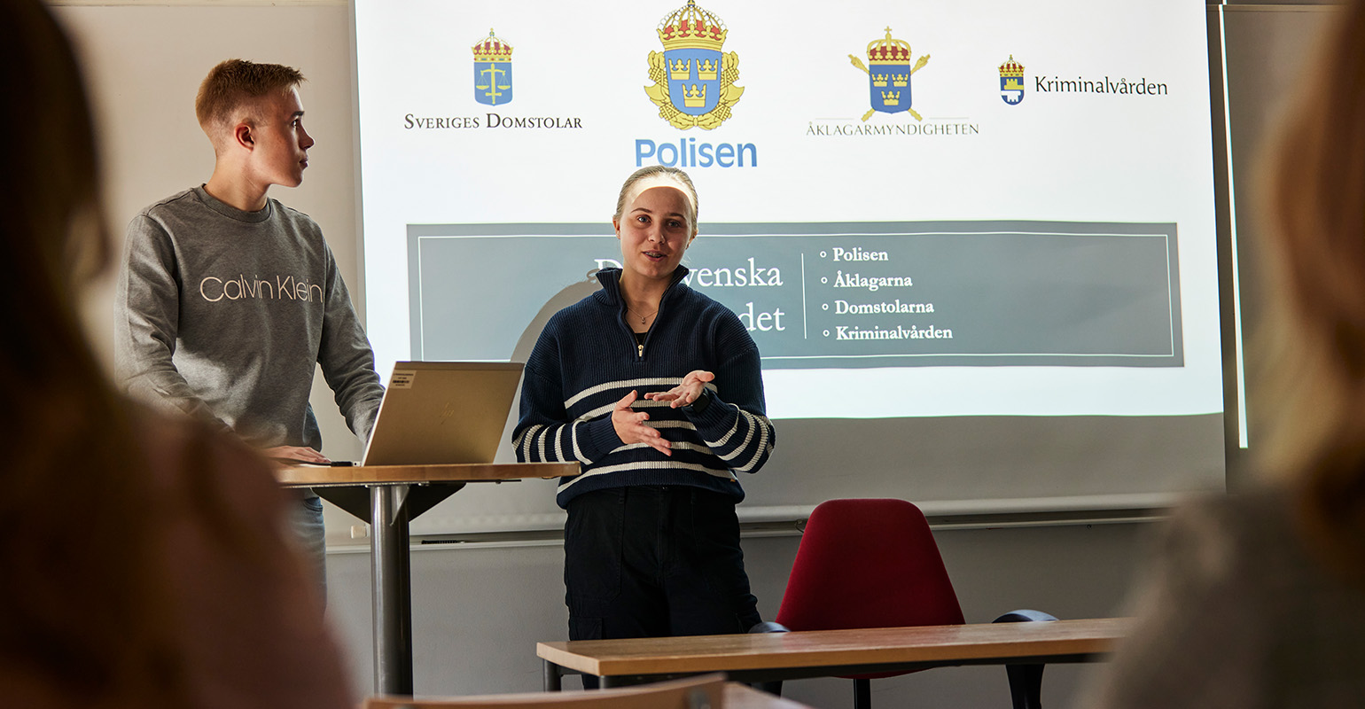 Två elever som föreläser vid tavlan i klassrummet.